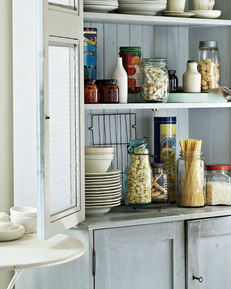 Kitchen with open cabinet displaying various food items and utensils.